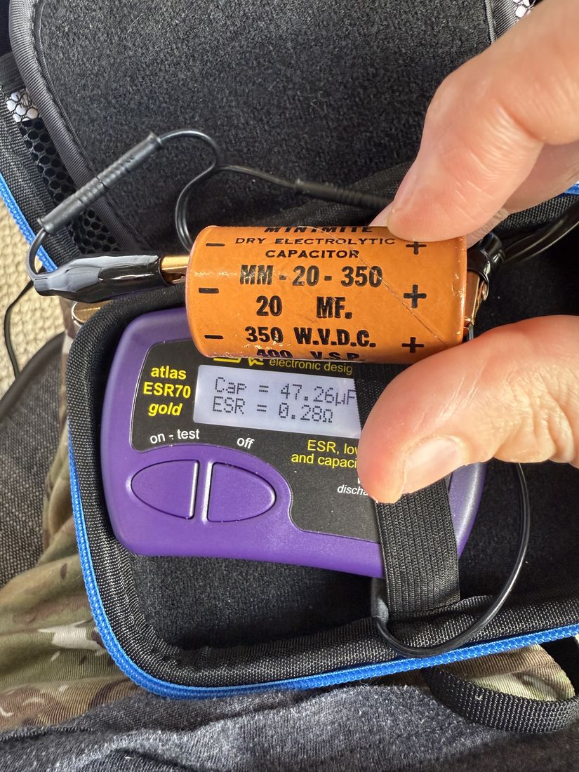 An orange 20 microfarad, 350 volt electrolytic capacitor clipped to a handheld ESR meter, whose screen reads 47.26 microfarads and 0.28 ohms.