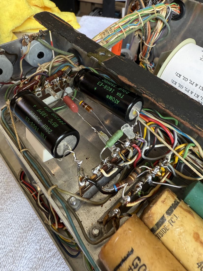 Two new black electrolytic capacitors and a green film capacitor wired into the chassis beside older brown and cream components.