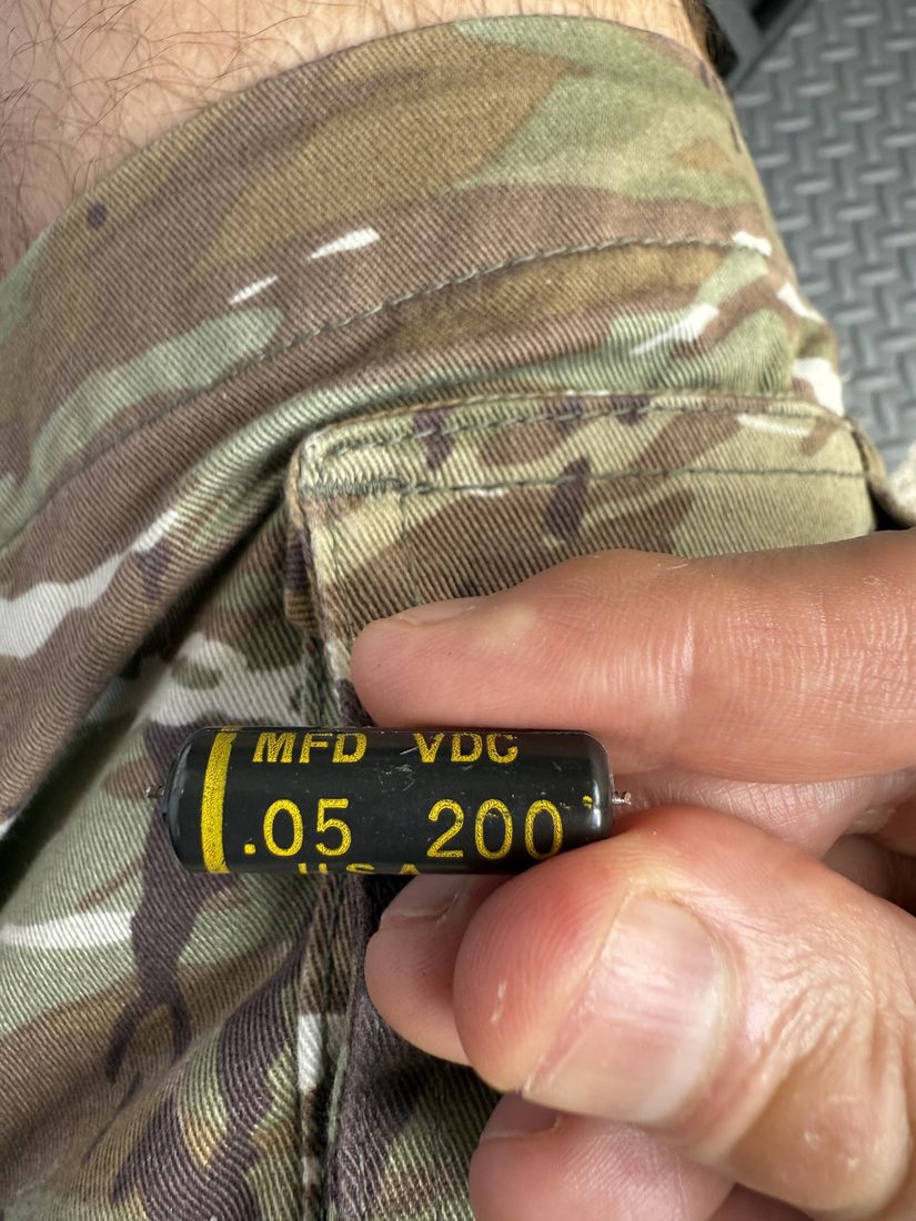 Fingers hold a small black tubular capacitor marked .05 MFD 200 VDC.
